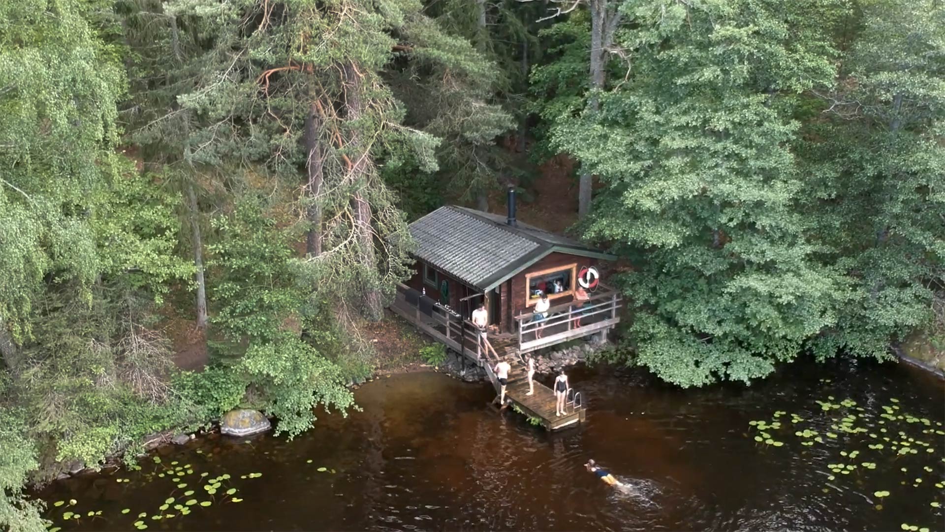 The lakeside sauna with guests swimming and enjoying the water